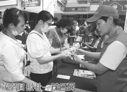 志愿者向市民游客派发安全文明旅游宣传资料。茂名日报社全媒体记者 李颜东摄<br>